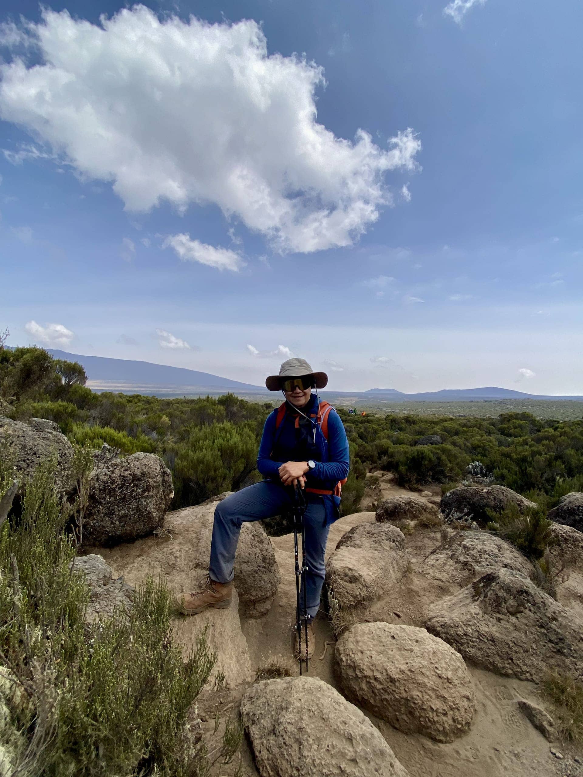 A guest resting on the trail with the snow-capped peak of Kilimanjaro behind